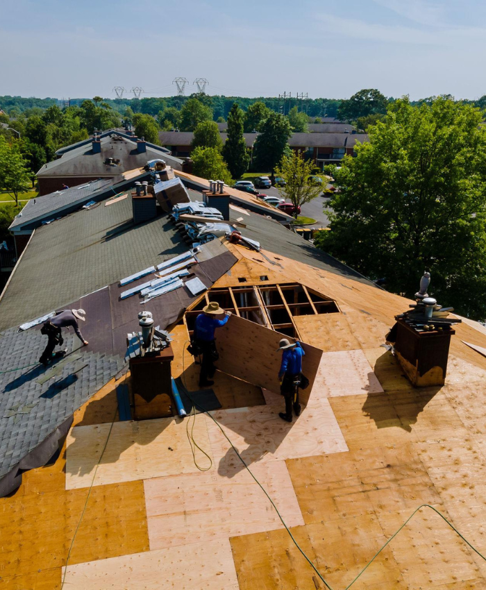 Roof repair workers replacing shingles and plywood on a residential roof in Amarillo, TX, showcasing essential roofing services and maintenance.